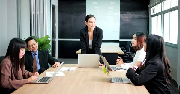 オフィスで取締役会のテーブルの周りでチームと話すアジアの上司のビジネス女性 — ストック写真