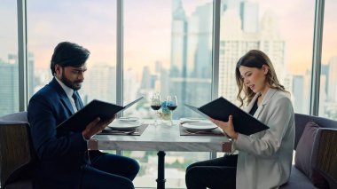 Mutlu iş çifti konuşuyor ve restoranın menüsünden bir menü seçmelerine yardım ediyor.