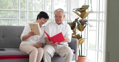 Mutlu Asyalı son sınıf çifti evdeki kanepede aile fotoğrafı albümü izliyor. Mutlu anlar