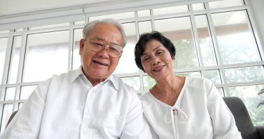 Mutlu Asyalı olgun yaşlı çift video ararken kameraya konuşuyor.