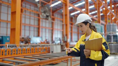 Fabrikada çalışan ve çelik metal stoklarını kontrol eden fabrika işçisi. Fabrika fabrikası elinde pano tutuyor.