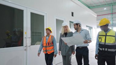 Depo ekibi depoda yürürken tartışıyor. Depo yönetimiyle çalışan çalışanlar büyük bir dağıtım merkezinde yürüyorlar.