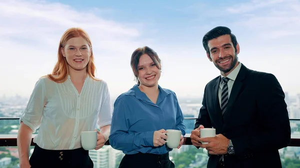 オフィスビルでコーヒーを飲みながら笑顔でカメラを見ている若いビジネスマンのチーム — ストック写真