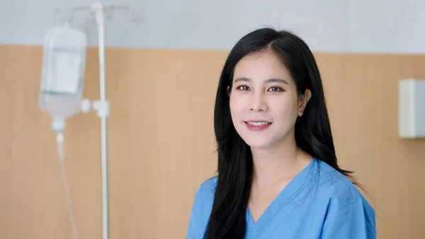 Закройте Усміхнене Обличчя Азіатки Пацієнтки Синьому Лікарняному Плащі Сидять Ліжку — стокове фото