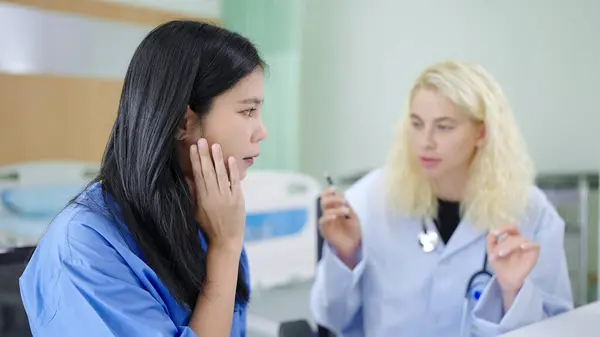 アジアの女性患者は白人女性の整形外科医と診療所で顔のしわの注射について相談に来る — ストック写真
