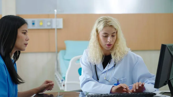 アジア女性と話す白人女性医師病院でのコンピュータに関する治療や治療情報の入力に関する患者相談 — ストック写真