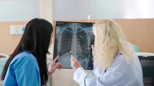 診療所での感染による肺肺炎とのエックス線フィルムについて話す女性医師と患者のバックビュー Covid Xrayテスト世界中で流行 — ストック写真