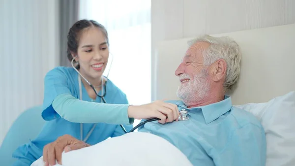 女护士持听诊器听老年男性病人的心率 快乐的护士长在医院用留声机测量老年男子的心跳 — 图库照片