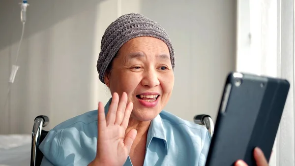 幸せなアジアの高齢者の患者が車椅子に座って 病院のタブレットでビデオ通話を行います 高齢者医療の概念 — ストック写真