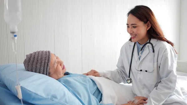 アジアの医師のケアは 病院のベッドで高齢女性の患者を訪問し フレンドリーな医師は 患者の手を保持し 彼女に話して 肯定的な感じ良いニュース 高齢者医療の概念 — ストック写真