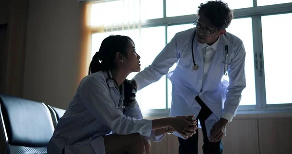 アジアの男性医師は 彼女は病院での患者治療についてストレスや不安を感じ 医師の女性に話す 慰めと奨励 — ストック写真