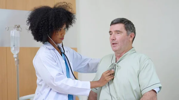 アフリカ系アメリカ人女性医師が病院の高齢男性患者と治療後の患者の症状を話し 再確認する — ストック写真