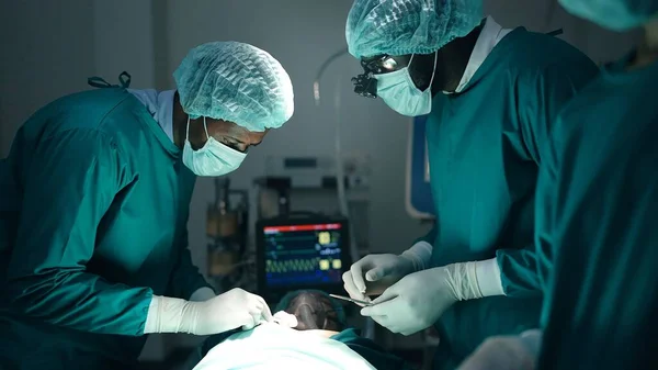 在手术室现代医院急诊部进行外科手术的非裔美国医生和外科医生专业小组 — 图库照片