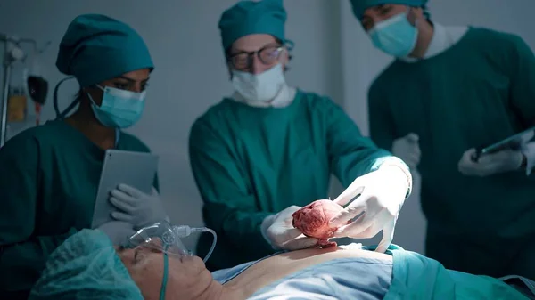 帮助一名躺在医院手术床上的男病人进行心脏手术的专业医疗小组 — 图库照片