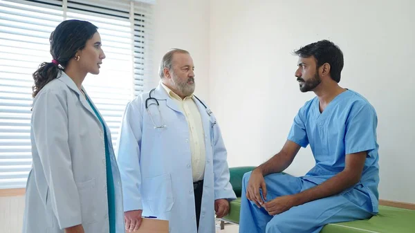 インドの男性患者が病院で医師と治療されていることを話し 奨励する専門の女性医師とアジアのシニア男性医師 — ストック写真