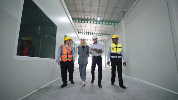 Group of factory warehouse workers walking and talking in warehouse for work wearing safety hardhats helmet inspection at warehouse