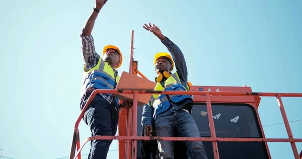 Güvenlik üniforması giyen ve konteynır terminalinde çalışan iki profesyonel Afrikalı endüstriyel mühendis. Meslektaşlar lojistik operasyonlar hakkında konuşuyor