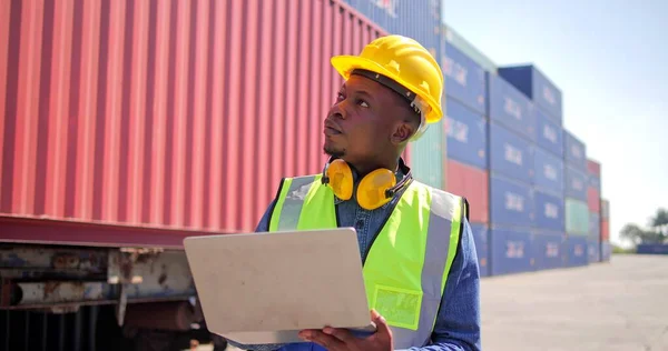 Black African man engineer using laptop control checking container from cargo freight for import and export , support logistics transportation concept