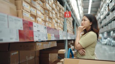 Asyalı kadınlar mobilya deposundaki ürün için büyük bir depodaki raflardan alışveriş yapıyorlar.