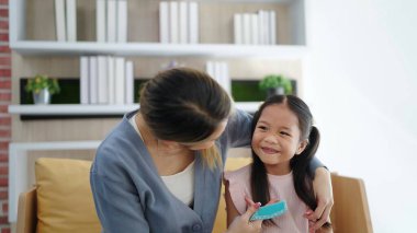 Mutlu ve sevgi dolu bir aile Asyalı anne ve kız evdeki oturma odasında kanepede oturarak iyi vakit geçiriyorlar.