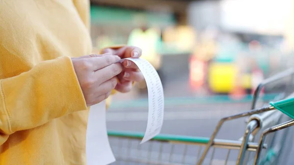 Bakkal arabasındaki faturayı kontrol eden kadının elini kapat. Süpermarketten alışveriş yaptıktan sonra
