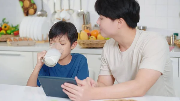 Padre Asiático Mirando Pequeño Hijo Bebiendo Leche Vidrio Cuarto Cocina —  Fotos de Stock