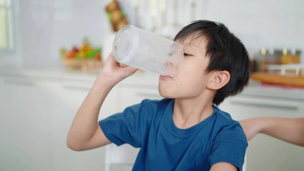 朝学校に行く前に家で牛乳を飲んでいるアジアのかわいい学生少年 牛乳を飲む子供のコンセプト — ストック写真