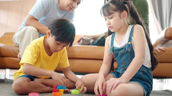 アジアの家族は家のリビングルームで一緒に休日に時間を過ごす 活動関係 若い二人の子供の娘と息子は異なる色のおもちゃで遊ぶ — ストック写真