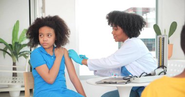 Afro-Amerikalı çocuklar klinikte ya da hastanede aşı oluyorlar ve el hemşiresi koruma için aşı enjekte ediyor. Çocuk aşısı kavramı