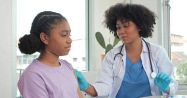 Afro-Amerikalı çocuklar klinikte ya da hastanede aşı oluyorlar ve el hemşiresi koruma için aşı enjekte ediyor. Çocuk aşısı kavramı