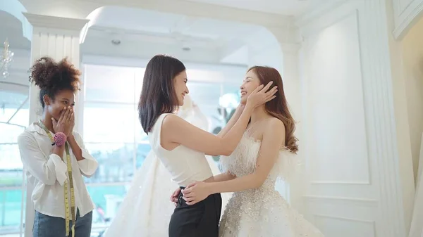 アジアの美しい新婦付添人は結婚式のスタジオで結婚式のための白いウェディングドレスを選ぶ花嫁になることであなたの友人を祝福します — ストック写真