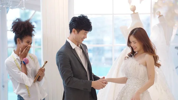 新郎はスーツを着て アジアの美しい花嫁は ウェディングスタジオでの結婚式のためのウェディングドレスの選択とフィッティング — ストック写真