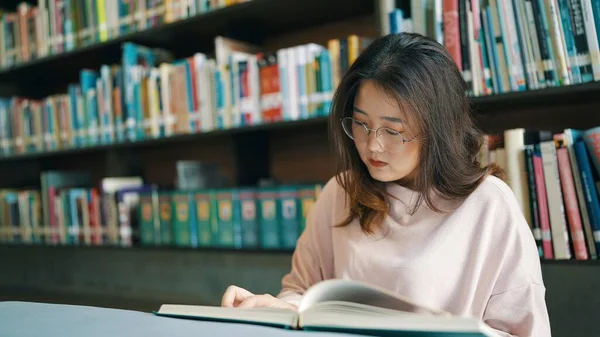Азійка Окулярах Сидить Читає Книгу Бібліотеці — стокове фото