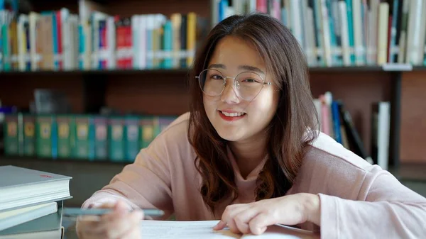 Smiling face of Asian woman student wearing glasses looking at camera