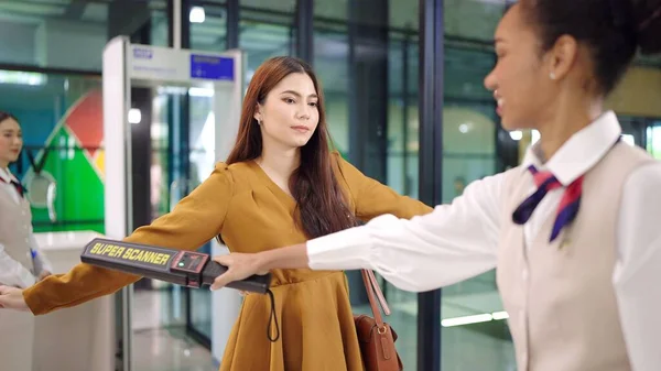 Security agent at airport check in gate with metal detector and scanner to passenger going on trip to terminal entrance