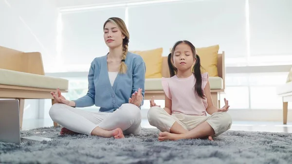 stock image Healthy lifestyle yoga practice. Mother and daughter doing yoga exercises sits in lotus position on floor in living room. Calmness concept