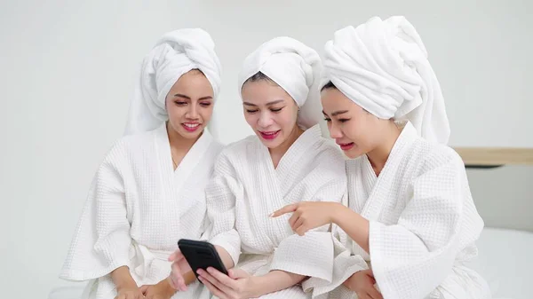 Trzy Koleżanki Szlafrokach Ręczniki Głowie Siedzące Łóżku Korzystające Smartfona Koncepcja — Zdjęcie stockowe