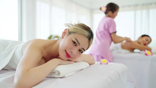 ロマンチックな高級スパでカメラを見てスパベッドの上に横たわる白いタオルで美しいアジアの女性の笑顔 ウェルネス ボディリラクゼーション療法 — ストック写真