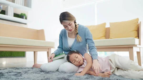 Mãe Asiática Lendo Livro Olhando Pequena Filha Dormir Seu Colo — Fotografia de Stock