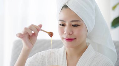 Hafta sonları evde maske soyarken doğal balla kaplıcaya giden kafası havluyla gezen güzel Asyalı genç kadınların yüzünü kapatın. Cilt bakımı kavramı