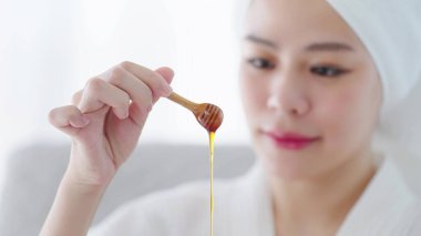 Kadınların arka yüzü maviydi. Kapalı el, kaplıca tedavisi için ahşap kaseye bal damlatan ahşap bal kepçesi tutan bir kadın. Cilt bakımı kavramı