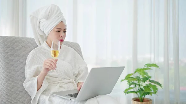 Młoda Azjatka Szlafroku Ręcznik Głowie Machając Film Laptopie Trzymając Szampana — Zdjęcie stockowe