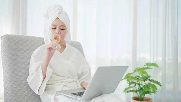 Azjatka Szlafroku Ręczniku Głowie Pije Szampana Podczas Pracy Laptopie Odpoczywa — Zdjęcie stockowe