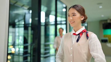 Havaalanındaki havayolu gişesinde uçağa binmeden önce yolcu temsilcisi olarak duran güzel Asyalı kadın yer personelinin gülümseyen yüzünü kapatın. Uçak yolculuğu ve ulaşım