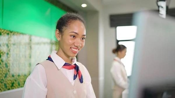 カウンターで航空会社のチェックインで働くためにコンピュータを使用して制服を着た若いアメリカのアフリカの女性の笑顔の顔を閉じます 航空交通の概念 — ストック写真