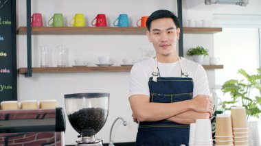 Çekici Asyalı baristanın portresi önlüklü, kolları bükülmüş kahve dükkanındaki kameraya bakarken gülümsüyor. Kahve dükkânı sahibi kavramı