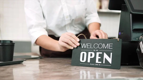 Business reopen again. Close up hands of owner or waitress holding open sign in cafe bar, coffee shop showing welcome to customer. Small business concept