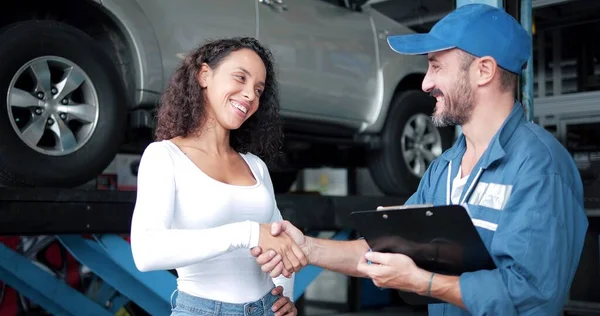 自動車修理店で女性のクライアントとの均一な握手で幸せな自動車整備士の男性 車のサービス メンテナンス ジェスチャーや機械式の概念 — ストック写真