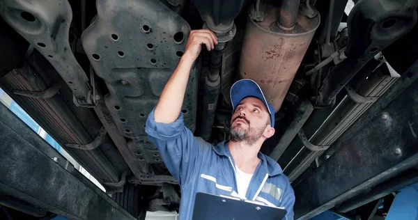 Kaukaski Mechanik Samochodowy Mundurze Trzymający Schowek Pod Samochodem Szukający Potencjalnych — Zdjęcie stockowe