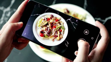 Organik salata tabağından fotoğraf çeken akıllı telefon ekranını kapat. Akıllı telefondan yiyeceklerin fotoğrafını çekmek. Sağlıklı gıda konsepti